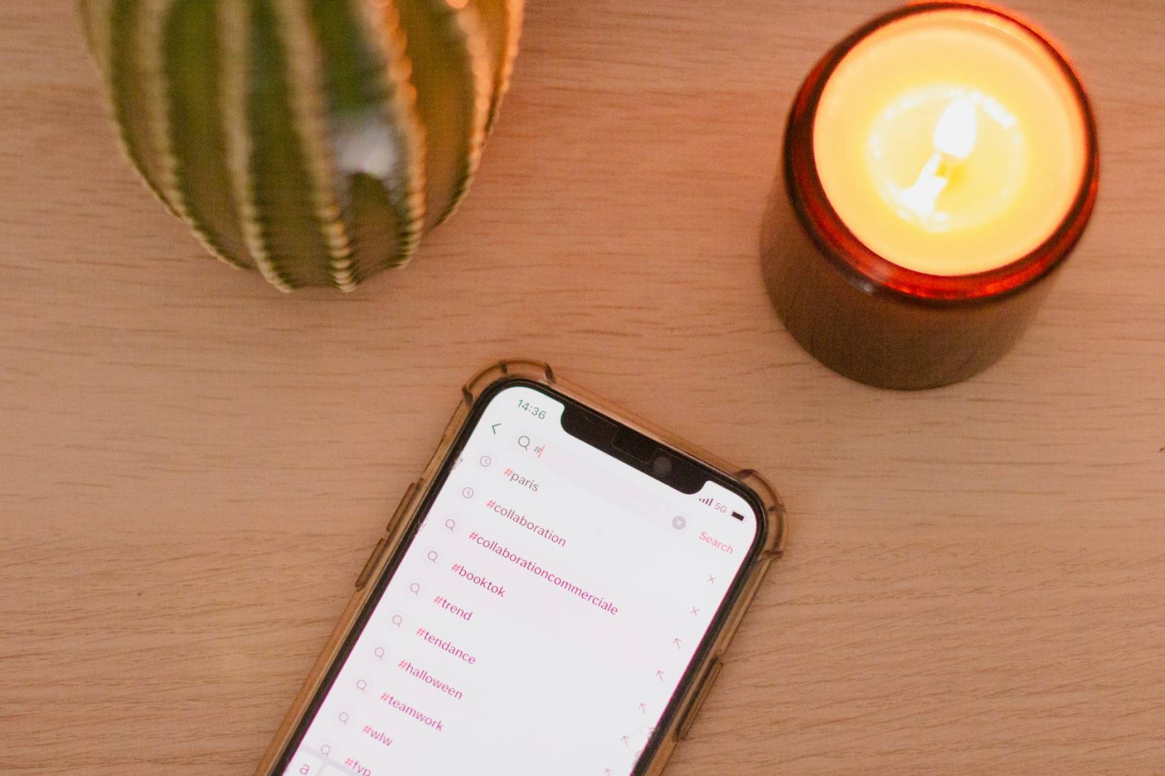 Smartphone displaying Instagram post with various hashtags, time at 14:36, and text related to collaboration, trends, Halloween, teamwork, 5G, and more.